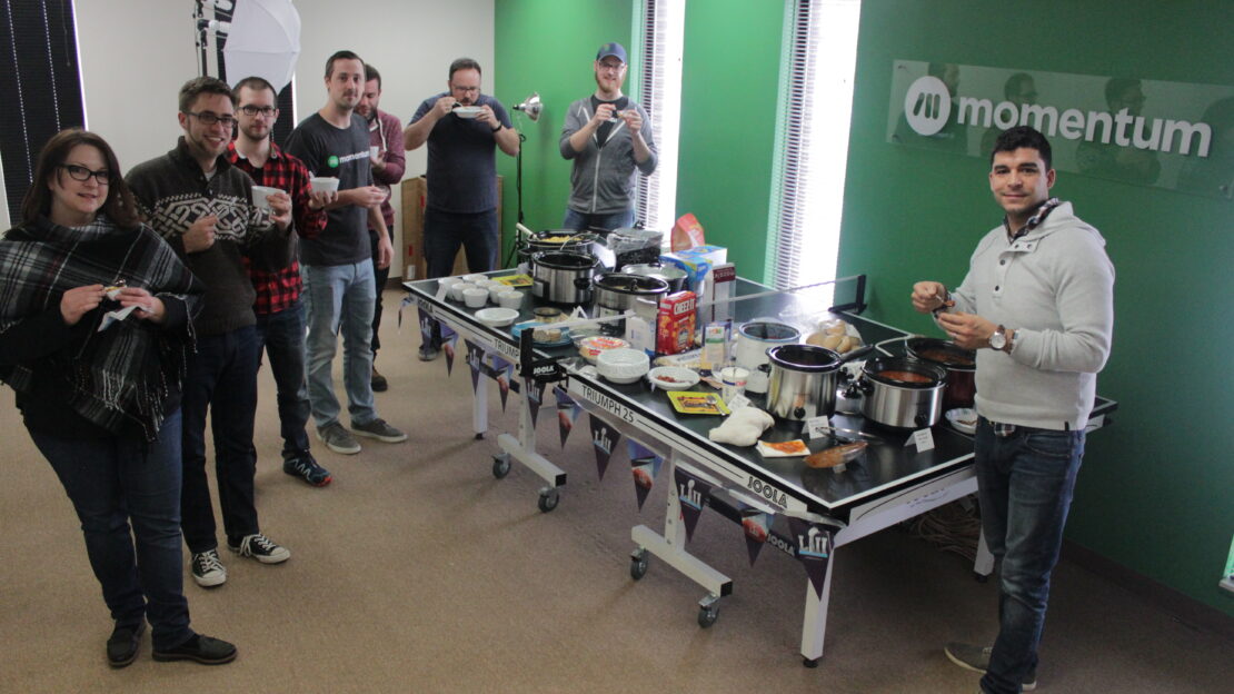 The Momentum team stands around a table full of chili
