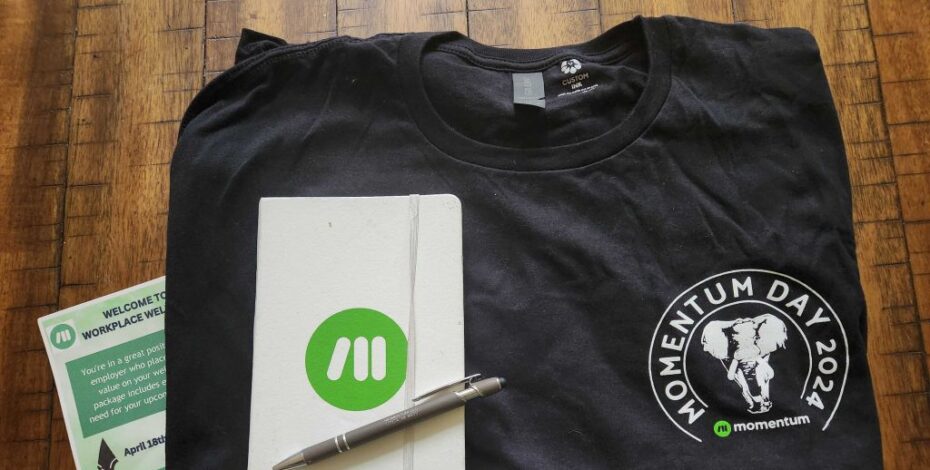 A t-shirt with a 'Momentum Day 2024' logo is on a table.