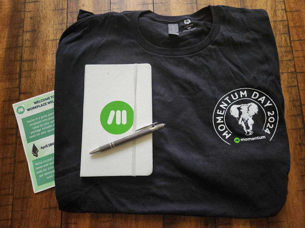 A t-shirt with a 'Momentum Day 2024' logo is on a table.