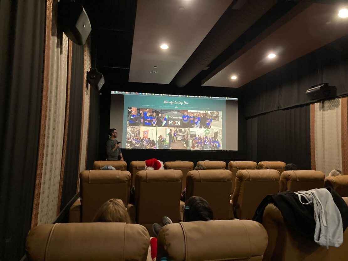 The Momentum team sits inside of a movie theater watching a presentation